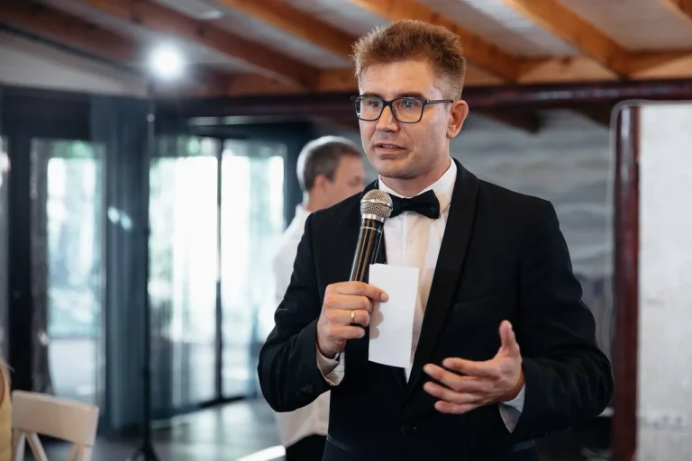 Ведучий Іван Панов веде банкет у залі, мікрофон і картка з текстом